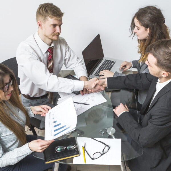 elevated-view-businessman-shaking-hands-with-his-partner-workplace